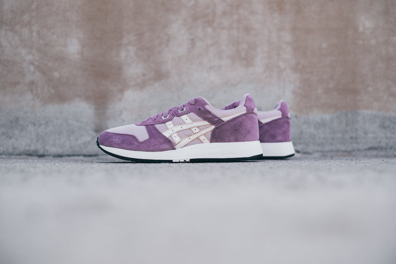 Stylish purple suede sneakers with white accents on urban concrete background.